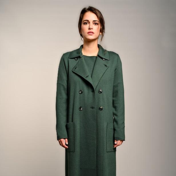 Model mit grüner Hose, grünem Oberteil und grünem Mantel.
