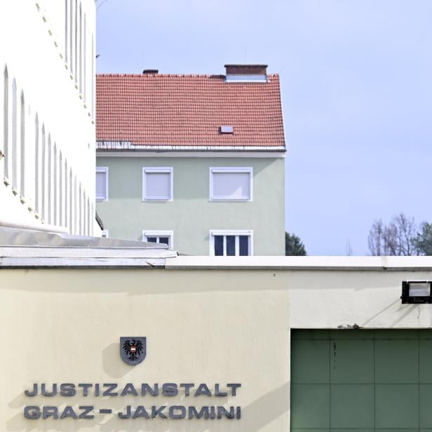 Die Justizanstalt Graz-Jakomini von außen mit einem Kirchturm im Hintergrund.