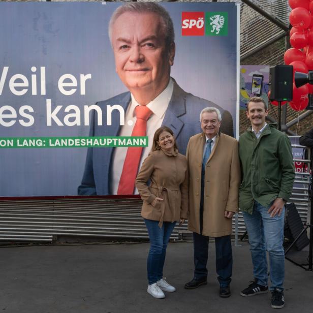 Drei Personen vor Plakat