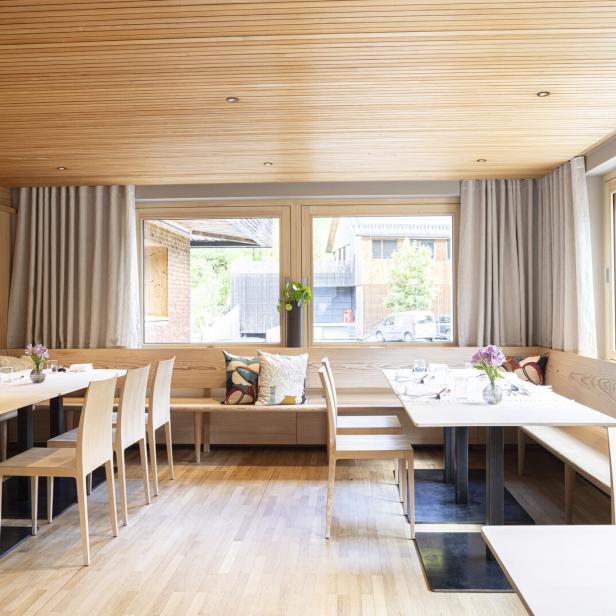 Ein Speiseraum mit Holzböden, Holztäfelung und Tischen mit Sitzbänken.