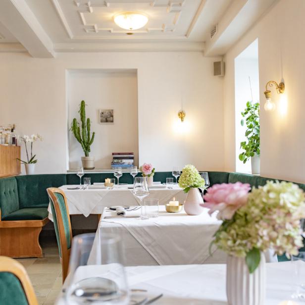 Ein elegant gedeckter Tisch in einem hellen Restaurant mit grünen Akzenten.