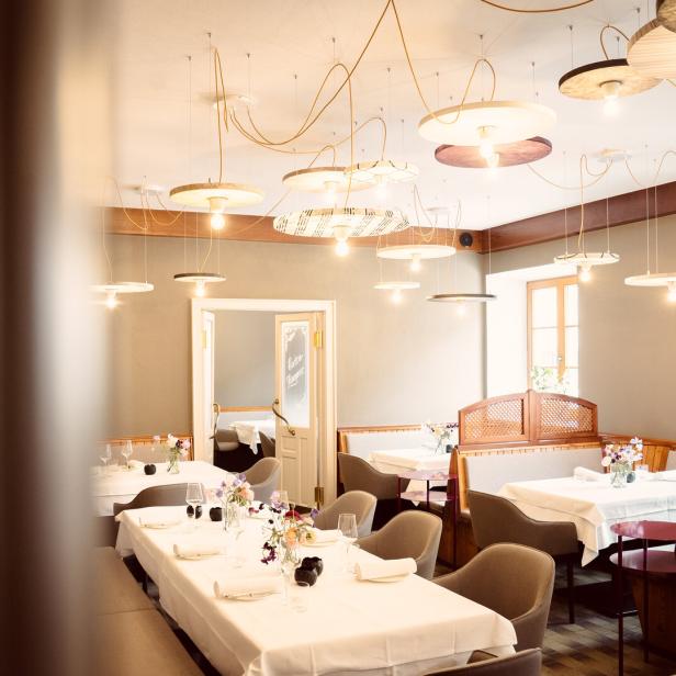 Ein elegant gedeckter Tisch in einem hellen Restaurant mit modernen Lampen.