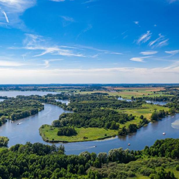 Eine Flusslandschaft mit grünen Ufern unter einem blauen Himmel mit Wolken.