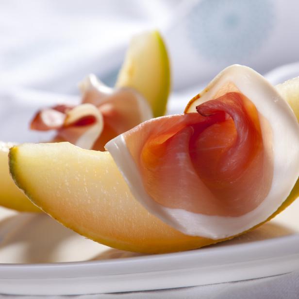 Cantaloupe-Melone mit Prosciutto auf einem weißen Teller.