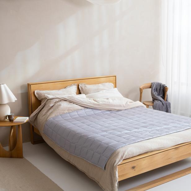 Ein heller Raum mit einem Holzbett, einem Holzstuhl, einem Nachttisch und einem Stuhl.