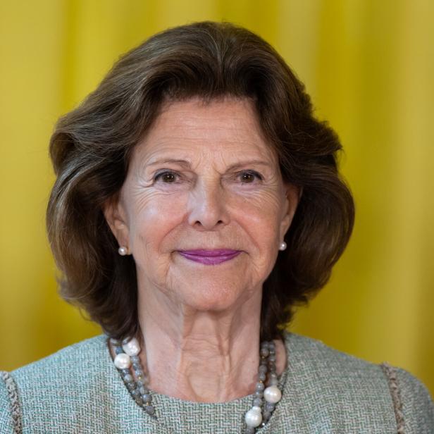Ein Porträt von Königin Silvia von Schweden vor einem gelben Hintergrund.