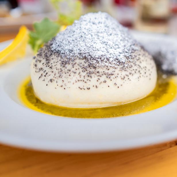 Ein Germknödel mit Mohn und Puderzucker auf einem Teller.