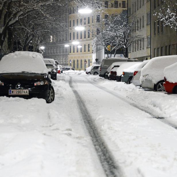 Eine Straße mit parkenden Autos, die mit Schnee bedeckt sind.