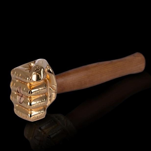Ein goldener Hammer mit einem Griff aus Holz liegt auf einer schwarzen Oberfläche.