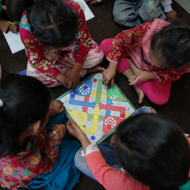 Vier Mädchen spielen in einem Kinderheim in Nepal ein Brettspiel.