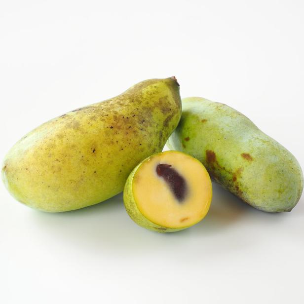 Zwei ganze Indianerbananen und eine halbe Frucht liegen auf einem weißen Untergrund.