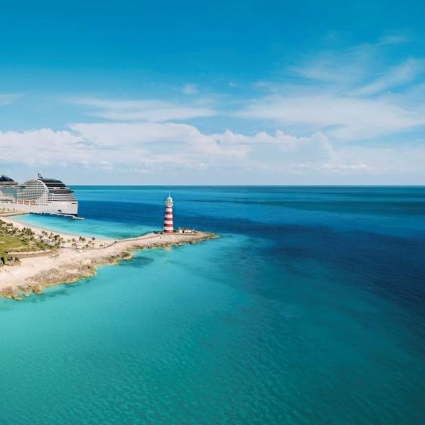 Kristallblaues Meerwasser mit einem Leuchtturm und einem Kreuzfahrtschiff im Hintergrund