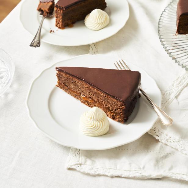 Ein Stück Wiener Sachertorte mit Schlagsahne auf einem Teller.