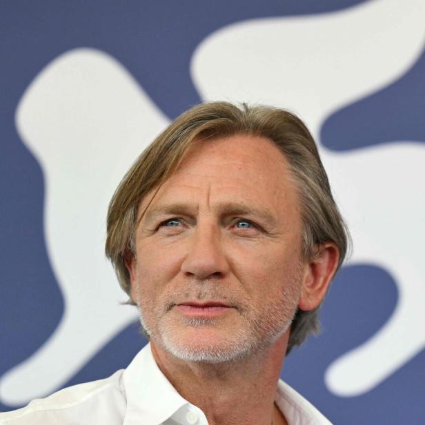 Porträt von Daniel Craig vor einem blauen Hintergrund mit weißem Logo.