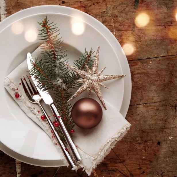 Ein festlicher Weihnachtstisch mit Teller, Besteck und Dekorationen.