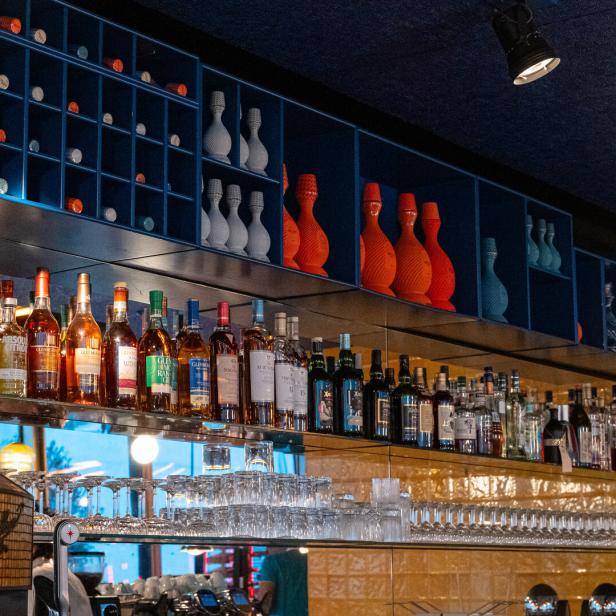 Eine Bar mit Spirituosenflaschen und dekorativen Vasen in Regalen.