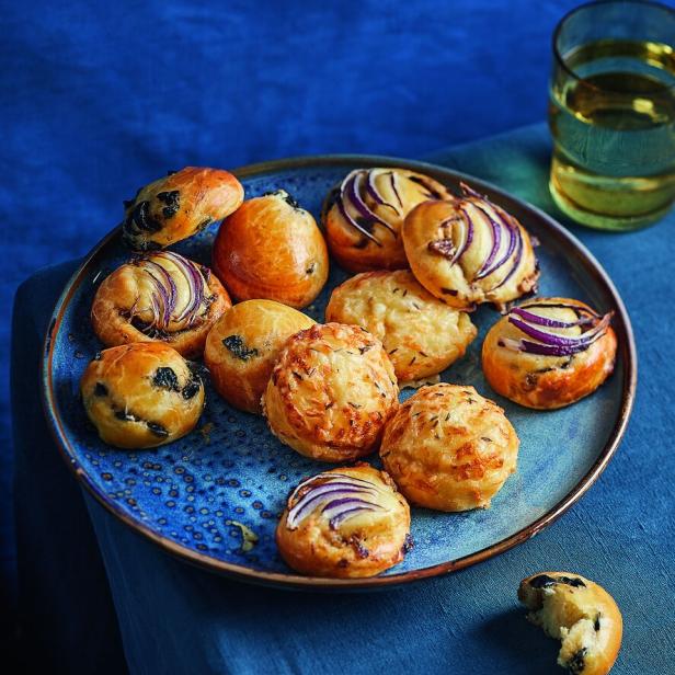 Cocktail-Brioches mit Zwiebeln, Käse und Kräutern auf einem Teller.