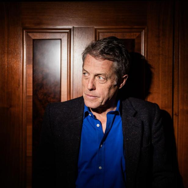 Porträt von Hugh Grant vor einer Holztür.