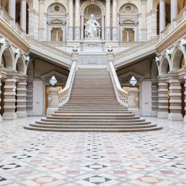 Die monumentale Treppe im Inneren des Justizpalastes in Wien führt zu einer Statue.