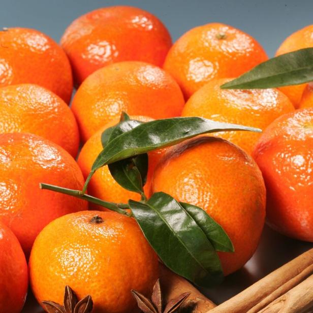 Mandarinen sind mit Zimtstangen, Sternanis und Nelken arrangiert.