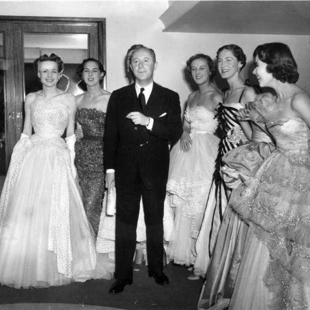 Christian Dior mit sechs Models in seinen eleganten Abendroben im Jahr 1950.