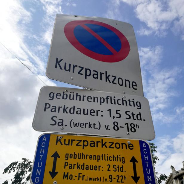 Mehrere Schilder weisen auf eine gebührenpflichtige Kurzparkzone hin; ein Pandabär ist auf dem Pfosten abgebildet.