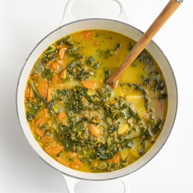 Eine Curry-Linsensuppe mit Grünkohl und Karotten in einem Topf.