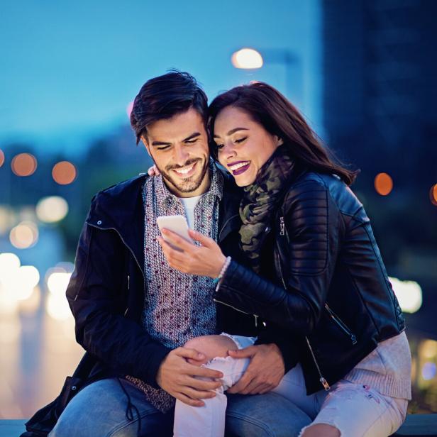 Pärchen verschickt gemeinsam Nachrichten am Smartphone.