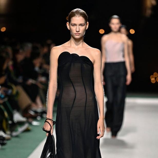 Ein Model mit einem schwarzen, schulterfreien Kleid von Victoria Beckham.