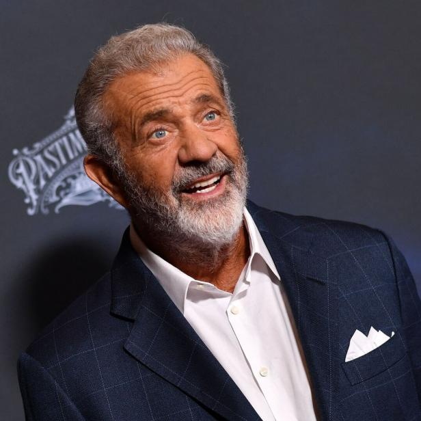 Mel Gibson lächelt in einem dunkelblauen Anzug.