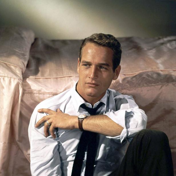 Der Schauspieler Paul Newman sitzt vor einem Bett.
