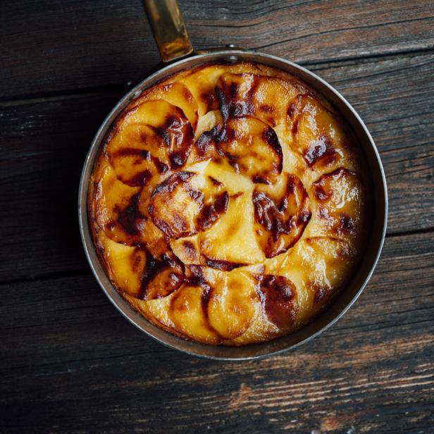 Ein Kartoffelgratin in einer Metallpfanne auf einem dunklen Holztisch.