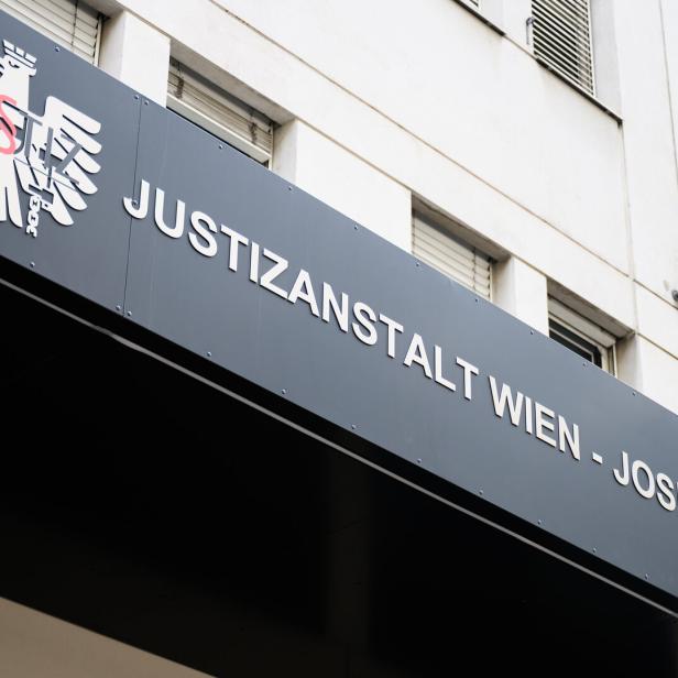 Schriftzug „Justizanstalt Wien - Josefstadt“ und ein stilisierter Adler an einer Gebäudefassade.