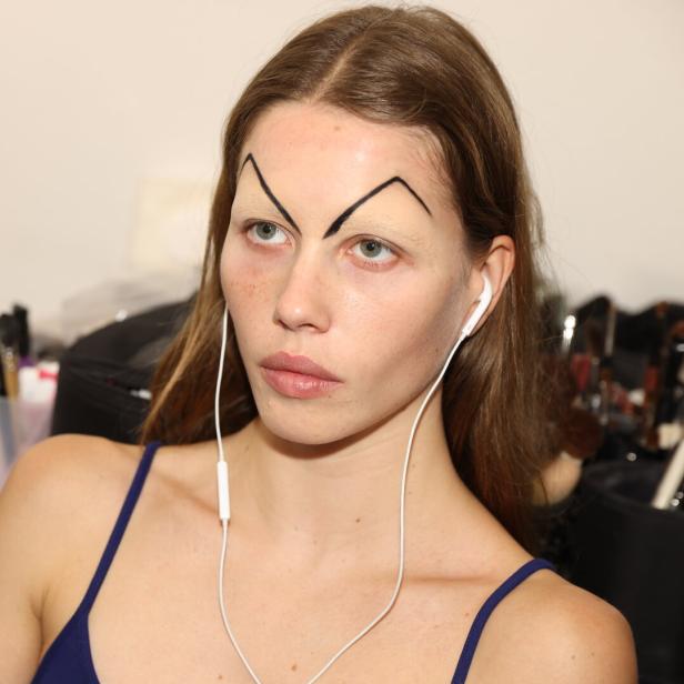 Ein Model mit ungewöhnlichem Augenbrauen-Make-up backstage bei der Mailänder Fashion Week 2025.