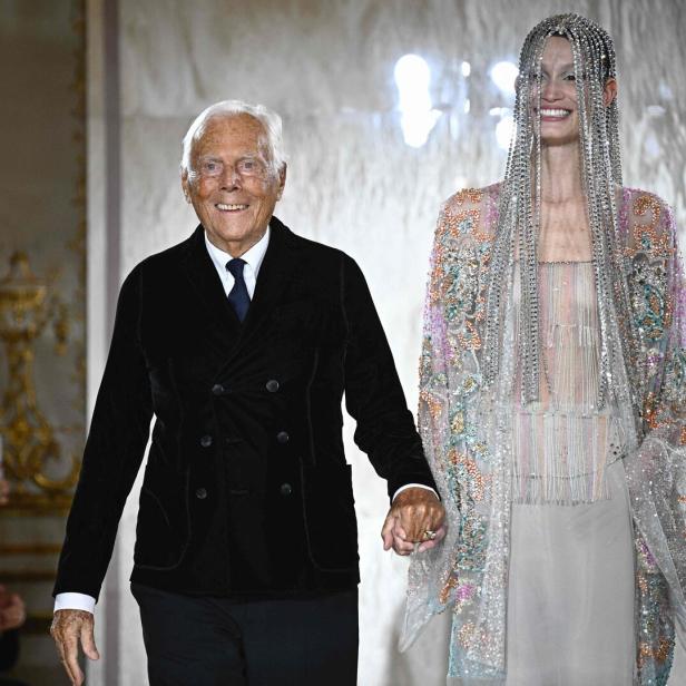 Giorgio Armani führt ein Model mit einem verzierten Kleid auf dem Laufsteg an der Modenschau.