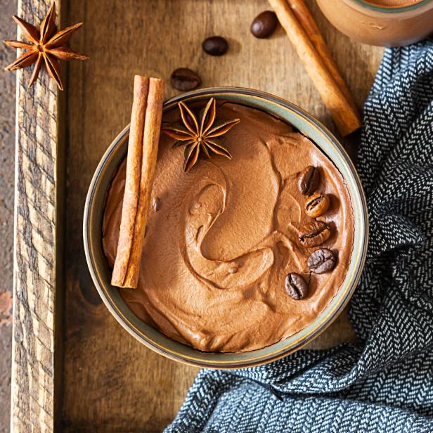 Eine Schüssel mit Schokoladenmousse, garniert mit Kaffeebohnen, Zimtstangen und Sternanis.