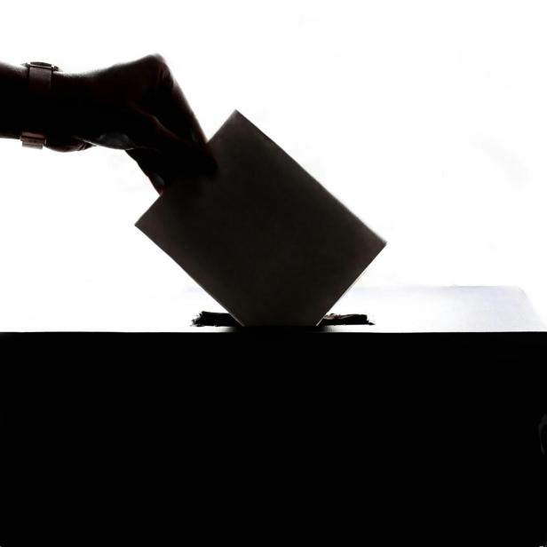 Eine Person wirft ihren Stimmzettel in die Wahlurne. 