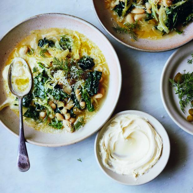 Eine Schüssel mit Bohnensuppe, Grünkohl und Dill, garniert mit Käse.
