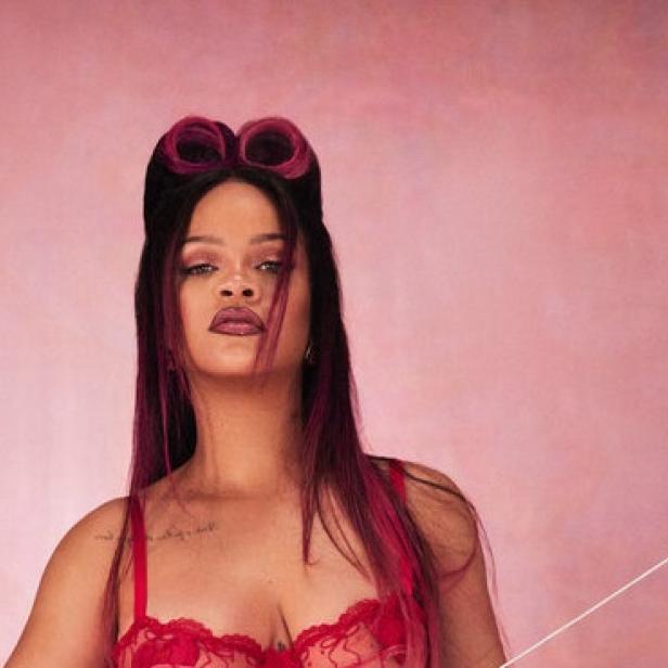 Rihanna posiert mit Pfeil und Bogen vor einem rosa Hintergrund.