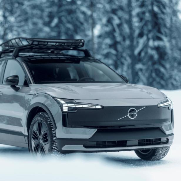 Ein grauer Volvo SUV mit Dachgepäckträger fährt durch eine verschneite Winterlandschaft.