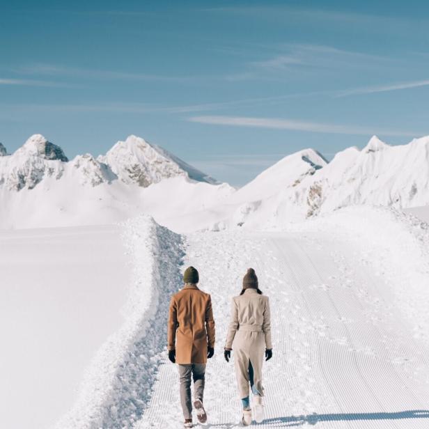 Ein Paar wandert im Winter in einer verschneiten Berglandschaft.