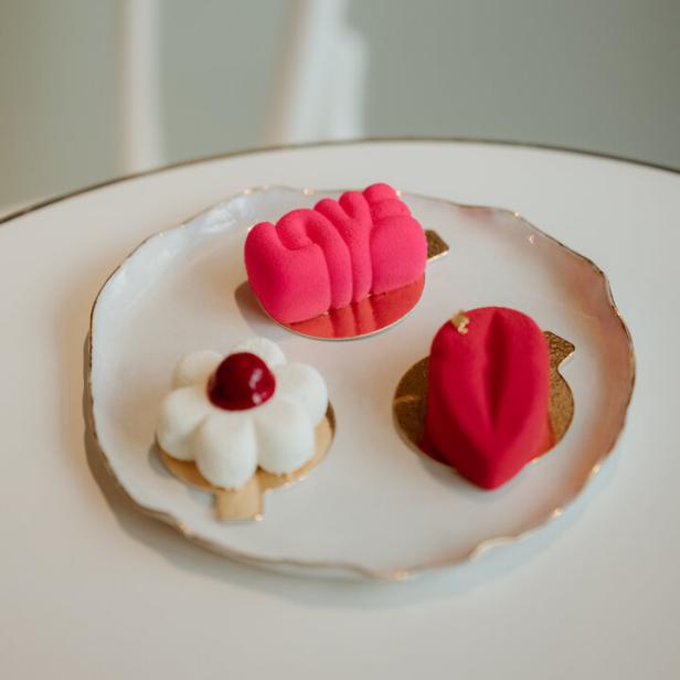Drei farbenfrohe, moderne Petit Fours auf einem weißen Teller.