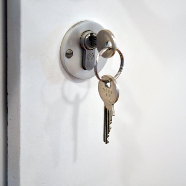 Schlüssel steckt im Schloss einer weißen Tür.