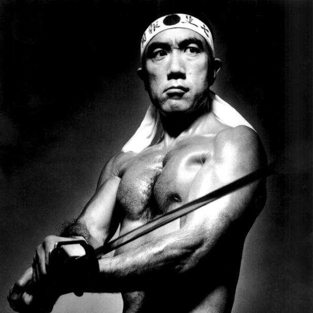 Yukio Mishima in der Rolle eines idealisierten japanischen Kriegers, der das Stirnband eines Kamikaze trägt und ein Schwert schwingt.