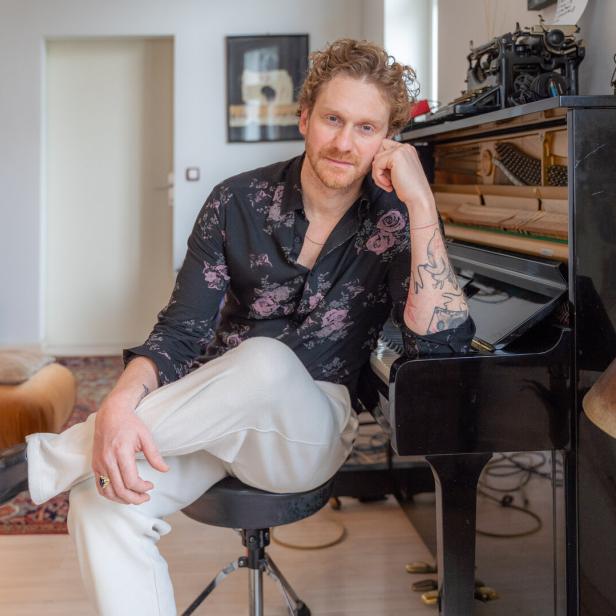 Lucas Fendrich sitzt an einem Klavier in einem Wohnzimmer.