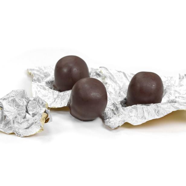 Drei Mozartkugeln liegen auf einer zerknitterten Silberfolie.