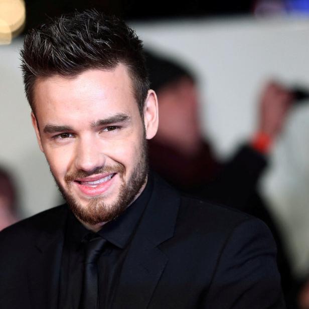 Liam Payne lächelt in einem schwarzen Anzug.