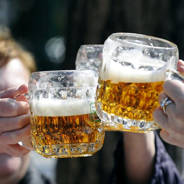Drei Personen stoßen mit großen Bierkrügen an.