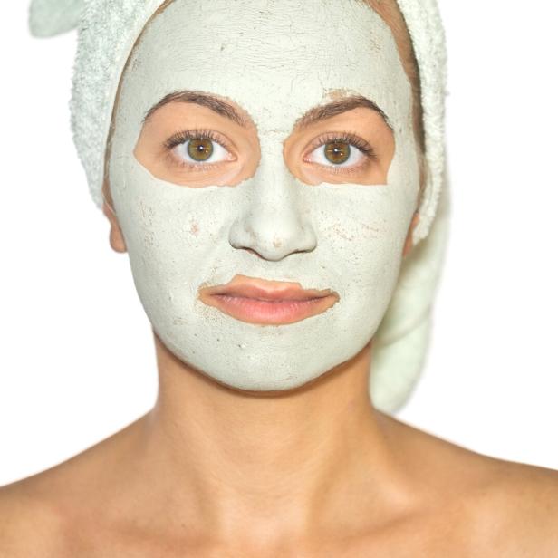 Eine Frau mit einem Handtuch auf dem Kopf und einer Gesichtsmaske.