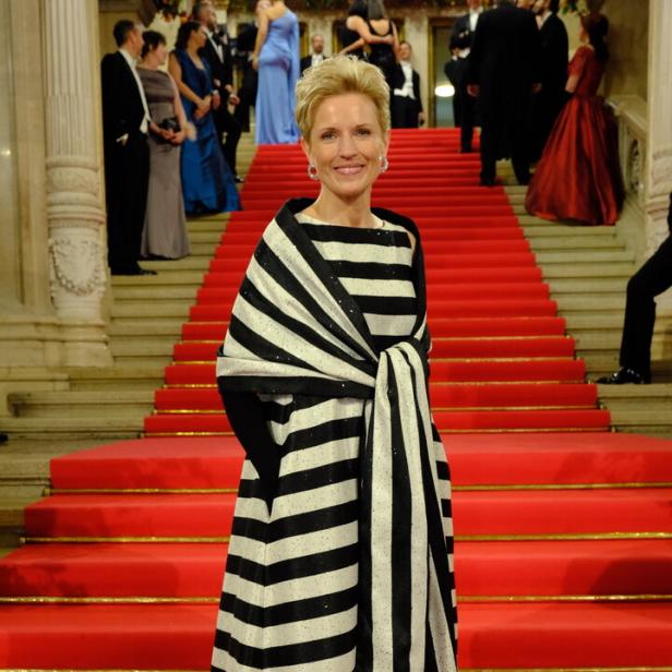 Eine Frau in einem gestreiften Kleid steht auf einer roten Treppe.